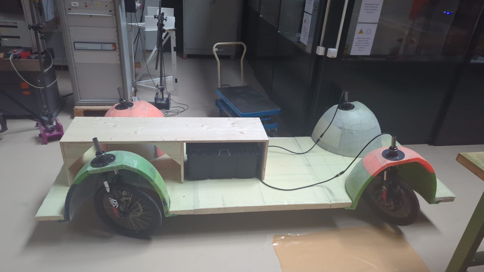 Side view of the SUV1 rolling chassis: flat composite plate, four eggshells over the wheels, battery tool box under the wooden seat box